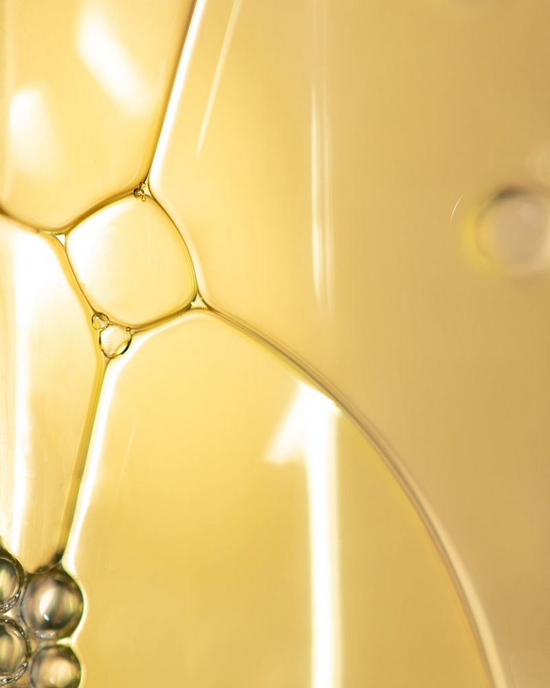 Uno scatto macro di bolle di detersivo liquido per piatti di colore giallo.