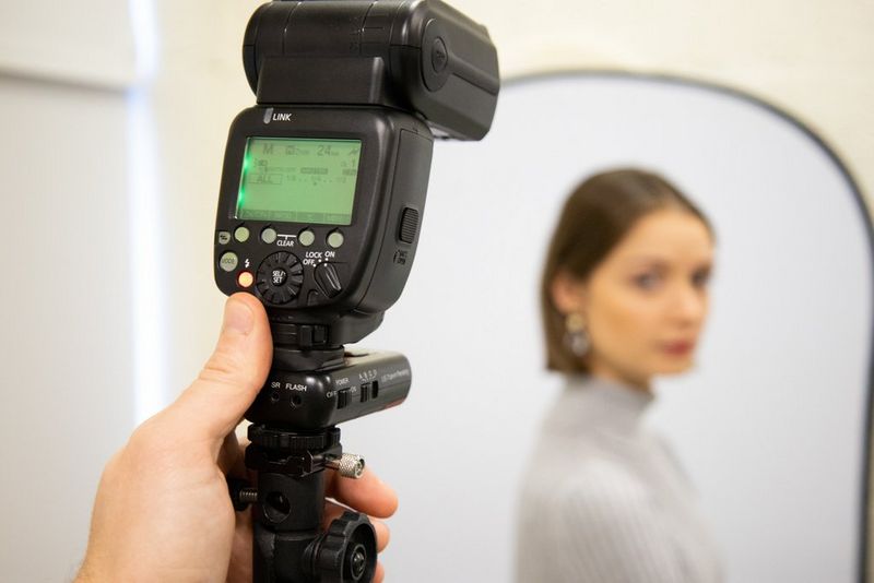 Iemand die de instellingen op de achterkant van een Canon Speedlite-flitser aanpast om een portret te fotograferen.