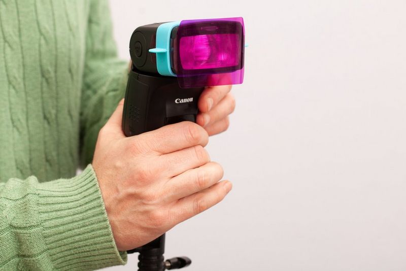 Een Canon Speedlite-flitser waarop een roze gelfilter is bevestigd.