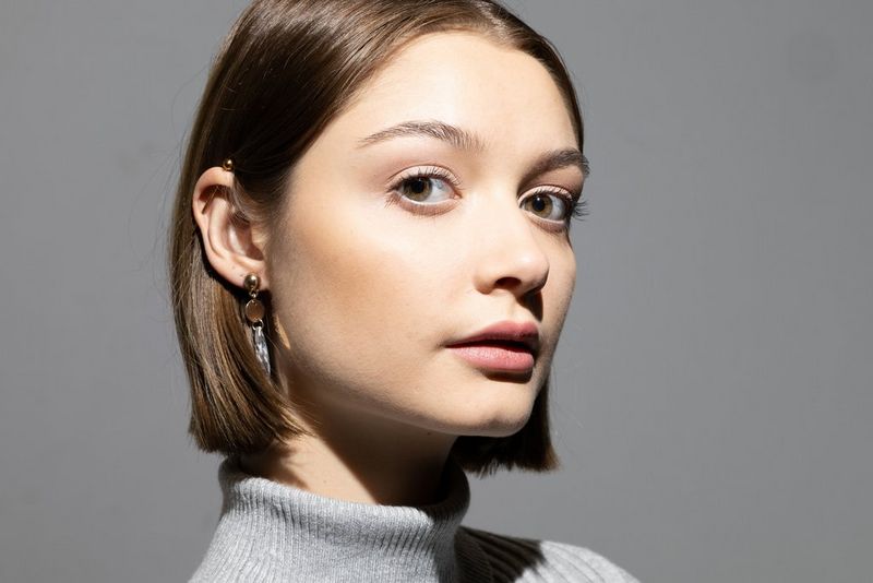 Portret van een vrouw met bruin haar, wiens gezicht wordt verlicht door een flitser.