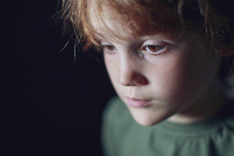 A portrait of a boy against a black background. 
