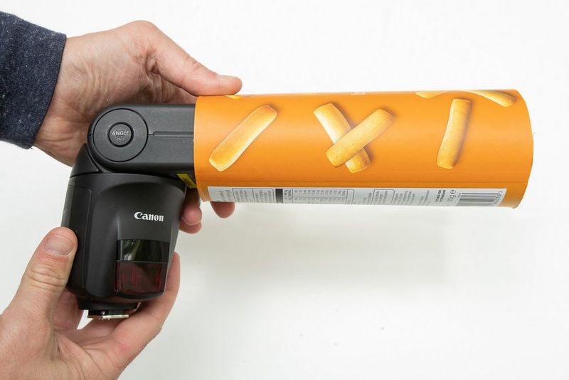 Мужчина надевает тубус для закусок на вспышку Speedlite.