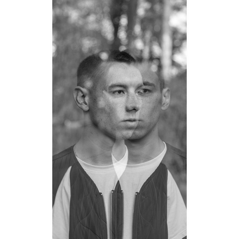 Een zwart-witfoto, met dubbele belichting, van een jonge man met kort haar.