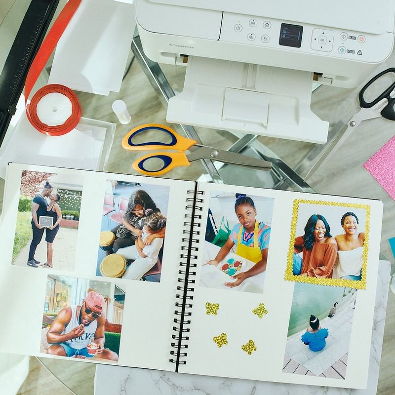 Een zelfgemaakt familiefotoalbum op een glazen tafel voor een Canon PIXMA-printer.
