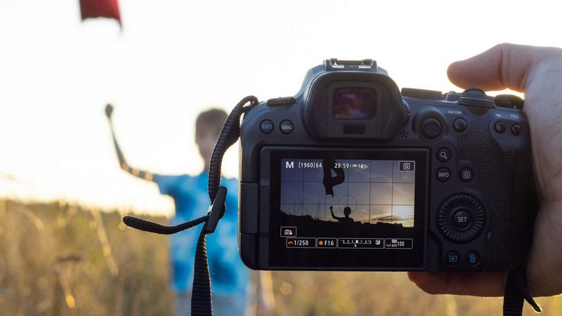 Una fotocamera Canon EOS R6 scatta l'immagine di un bambino che tiene palloncini in mano con il sole che tramonta sullo sfondo.