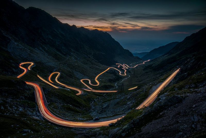 Light trails on a winding mountain road in evening light, clearly visible far into the distance. Taken by Piotr Skrzypiec on a Canon EOS R5.
