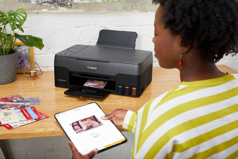 Een vrouw die met een tablet wireless print op een MegaTank-printer.