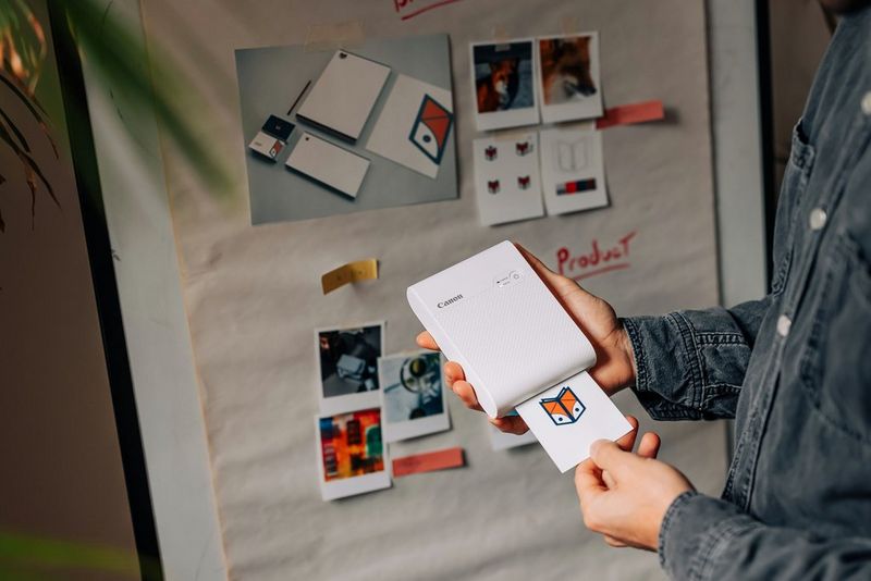 Osoba drži svoj SELPHY Square QX10 tvrtke Canon dok on ispisuje logotip za projekt.