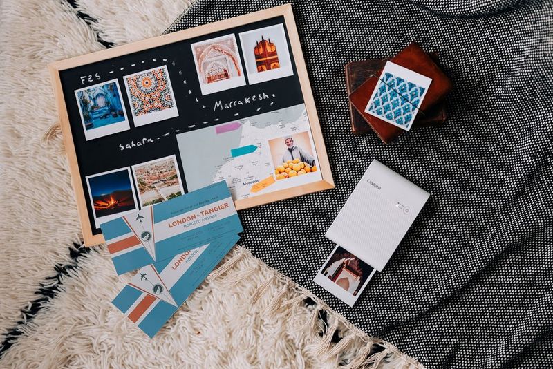 Ploča sa slikama s temom putovanja u Maroko koja prikazuje uzorke pločica i karte, pokraj pisača SELPHY Square QX10 tvrtke Canon.