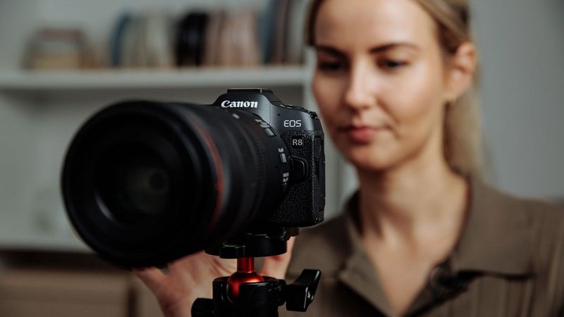 Een vrouw staat achter een Canon EOS R8-camera op een statief voor het filmen van voedsel.