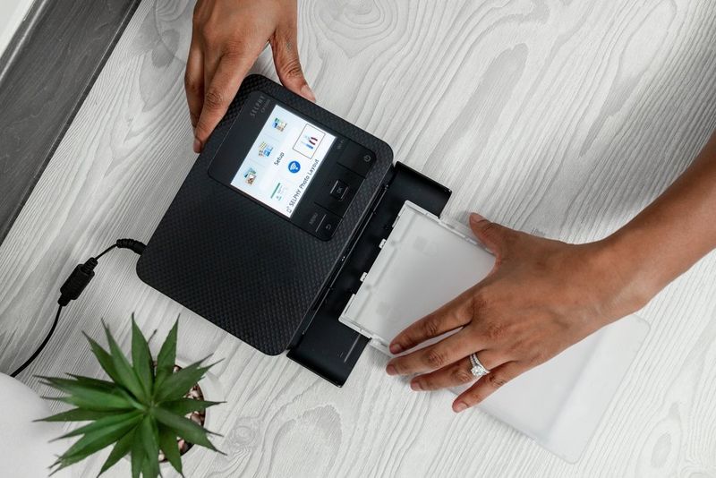 זוג ידיים הטוענות מחסנית לתוך ה-Canon SELPHY CP1500.