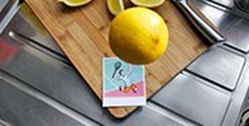A lemon hovers in the air above an illustrated print of a tennis player about to serve. The effect makes it look as if the player is about to hit the lemon.