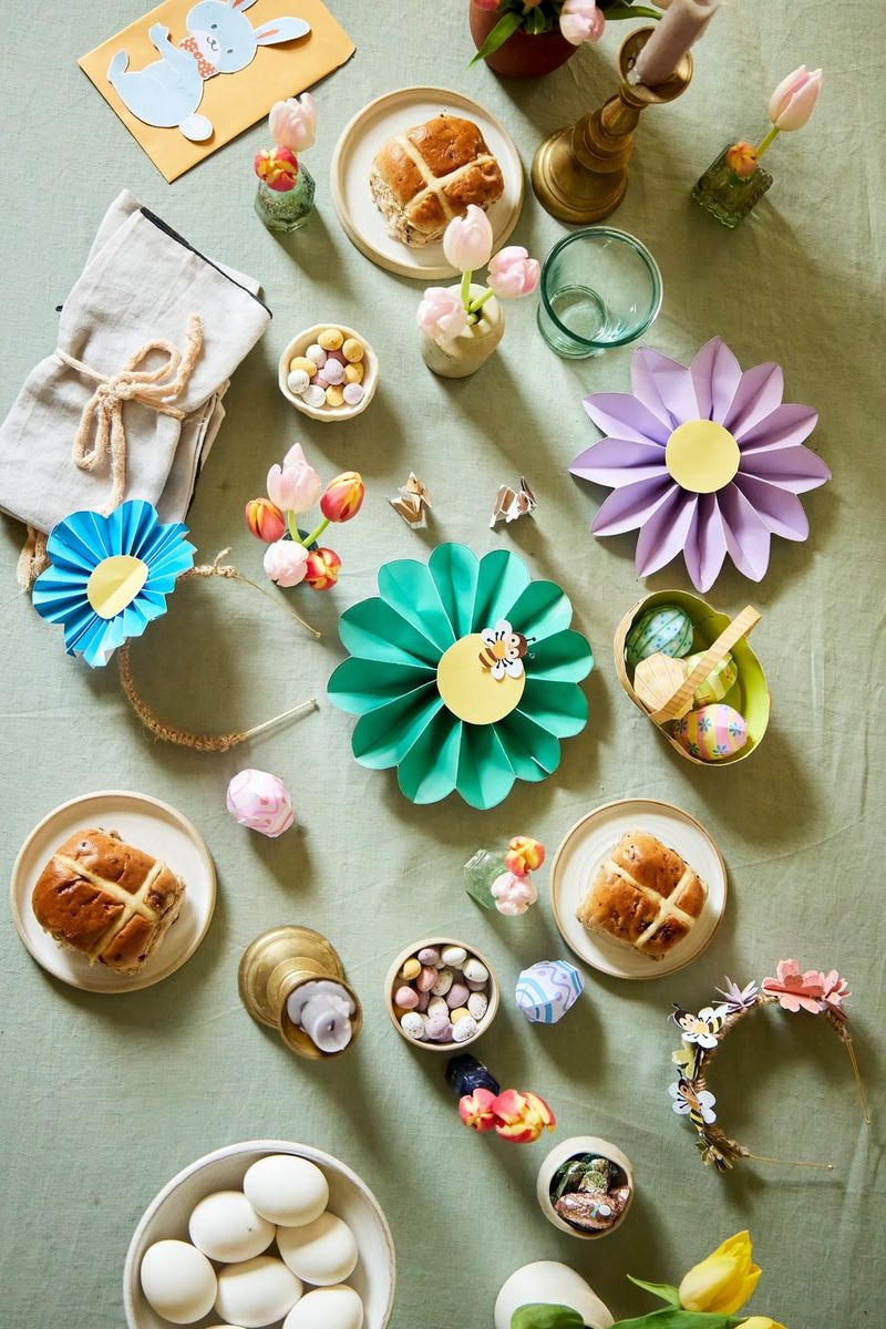 A table covered with Canon Creative Park papercraft decorations, flowers in vases and plates of food including eggs and hot cross buns.