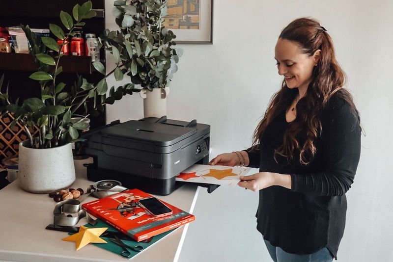 Žena s dlouhými hnědými vlasy vytahuje z tiskárny Canon vytištěnou šablonu s hvězdami.