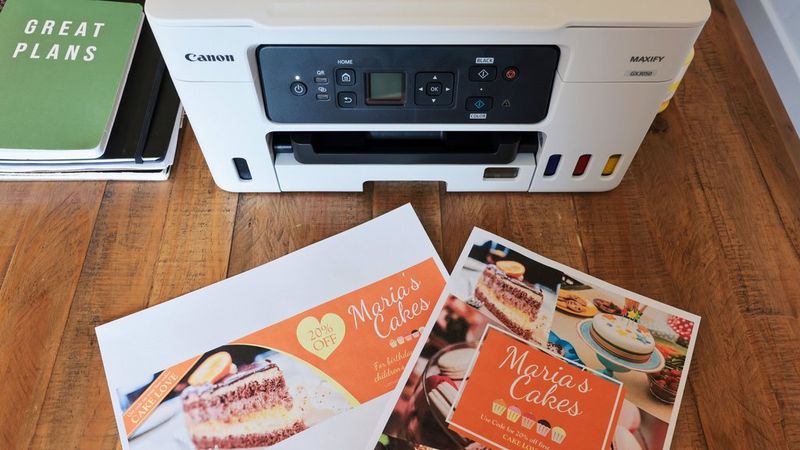 Odštampana Canon PosterArtist dizajnerska rešenja na radnom stolu ispred Canon MAXIFY štampača.
