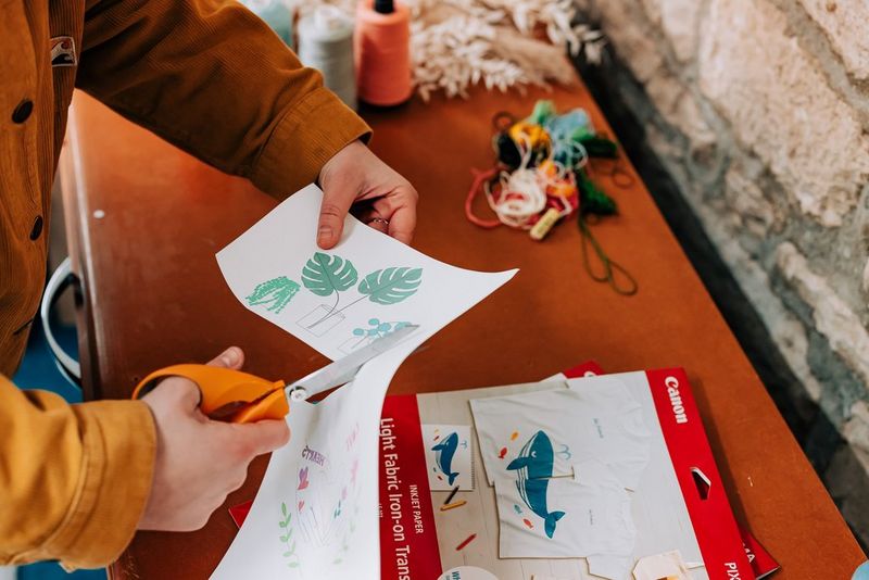 Женщина вырезает изображение комнатного растения ножницами.