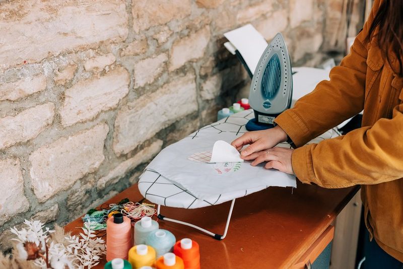 Женщина отделяет защитный слой от носителя для термопереноса, прикрепленного к белому куску ткани.