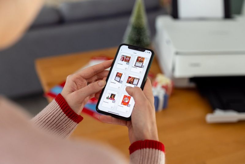 Een vrouw bladert door de kerstkaartsjablonen in de Easy-PhotoPrint Editor-app op haar smartphone.