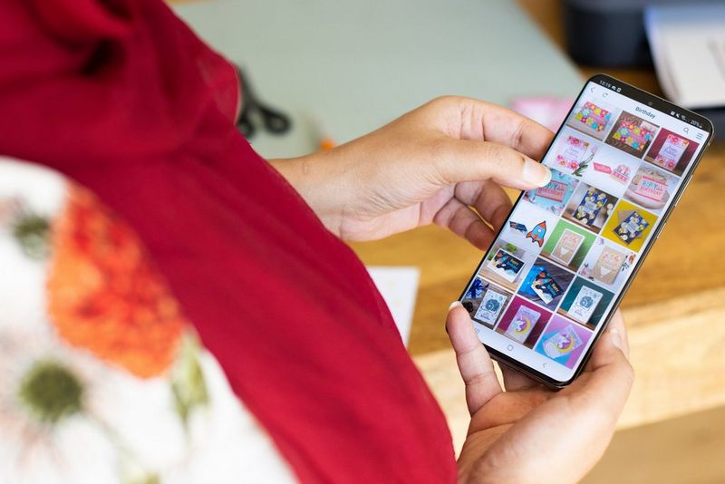 Une femme regardant des modèles de cartes imprimables sur un smartphone.
