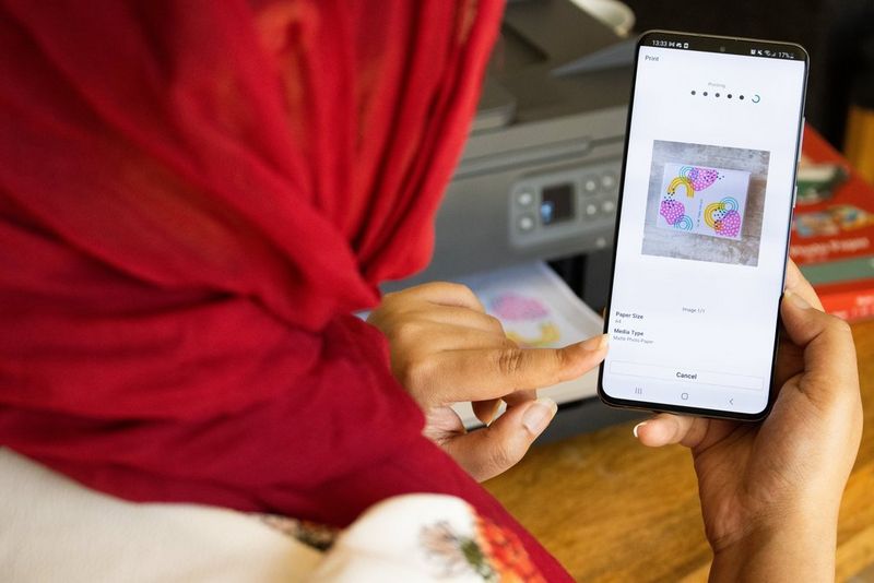 Une femme utilisant son smartphone pour imprimer une carte avec l'imprimante Canon PIXMA.