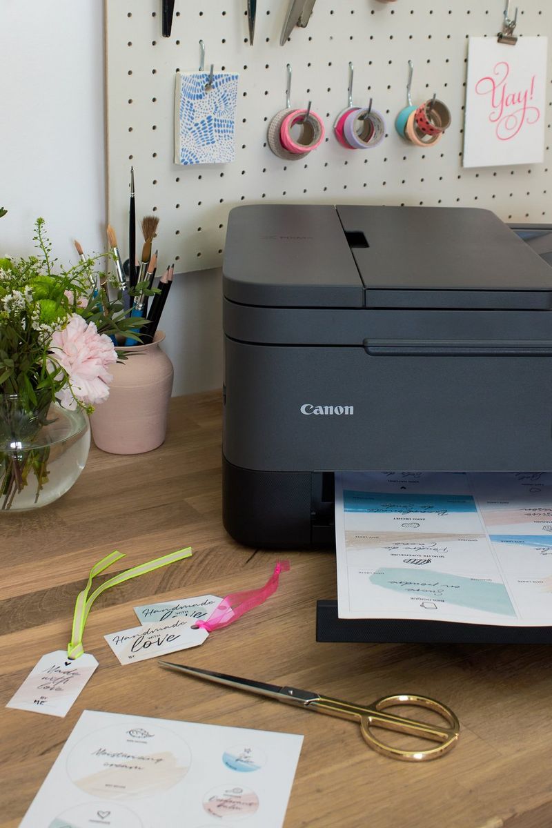 A printer sits on a desk next to a selection of printed labels and gift tags, finished with ribbon.