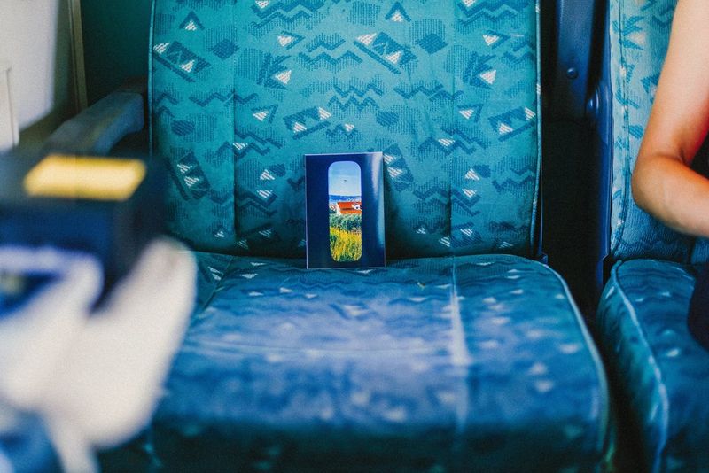 A single postcard size photo print, produced on a Canon SELPHY CP1500 printer, sits propped up on a train seat, showing a scene photographed through a train window by travel photographer Katie Edwards.