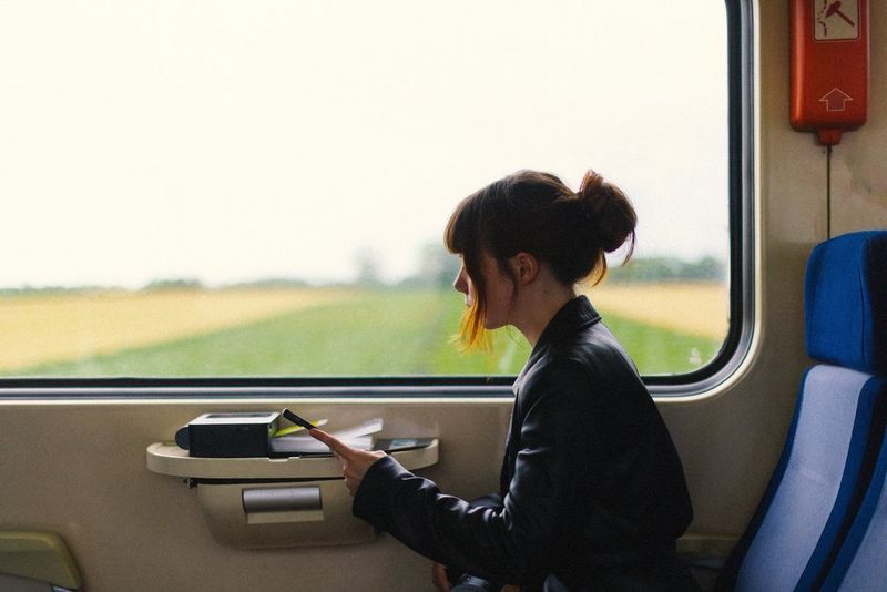 Travel photographer Katie Edwards sits on a train with a Canon SELPHY CP1500 portable photo printer on the table under the window alongside her.