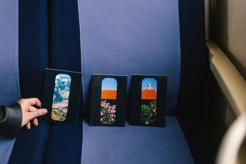 A hand reaches for one of three postcard-size photo prints propped up on a train seat, printed with a Canon SELPHY CP1500 portable photo printer.