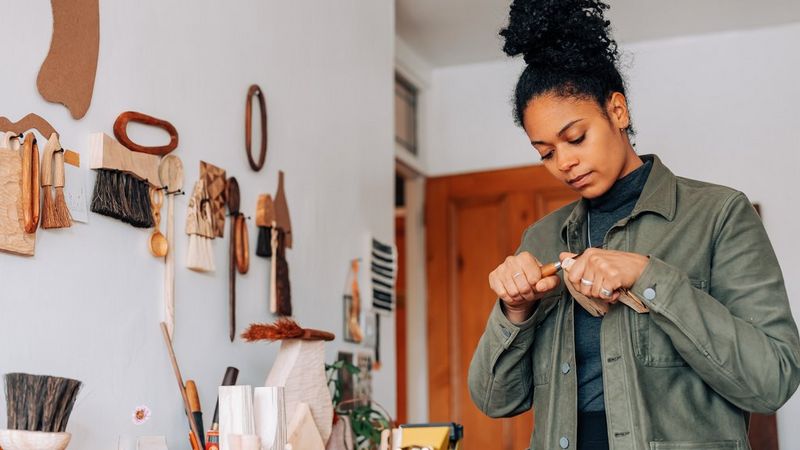 Mano di donna mentre intaglia un vaso in legno nel suo laboratorio.