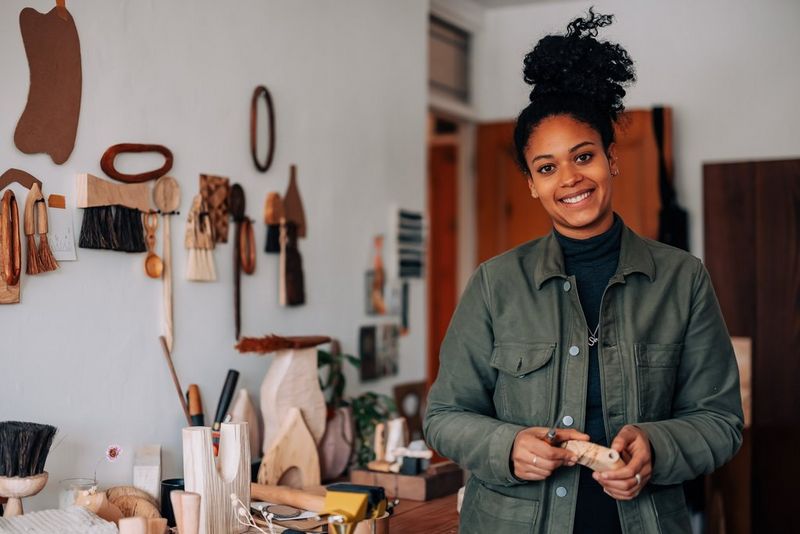 Donna che sorregge un vaso in legno in piedi nel suo laboratorio.