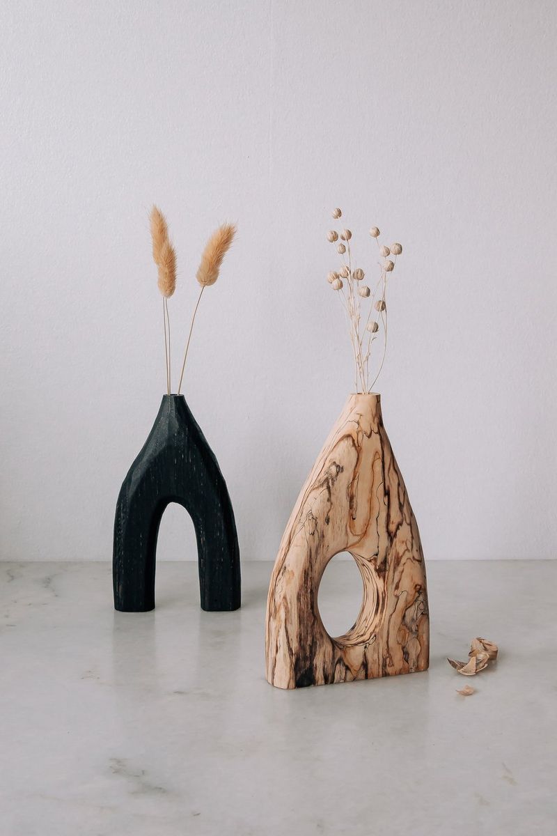 Due vasi in legno pieni di fiori bianchi con accanto trucioli di legno.