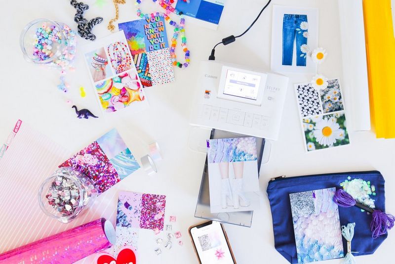 Un assortimento di materiali colorati per il fai da te e di stampe intorno a una stampante Canon SELPHY CP1300.