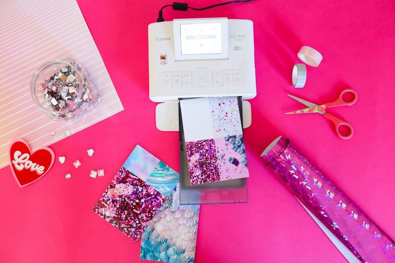 Una stampante Canon SELPHY CP1300 stampa un foglio con quattro diversi motivi glitterati.