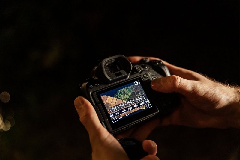 Par ruku prilagođava ISO postavke na fotoaparatu tvrtke Canon. Pozadina je potpuno tamna, što ukazuje na to da je noć.