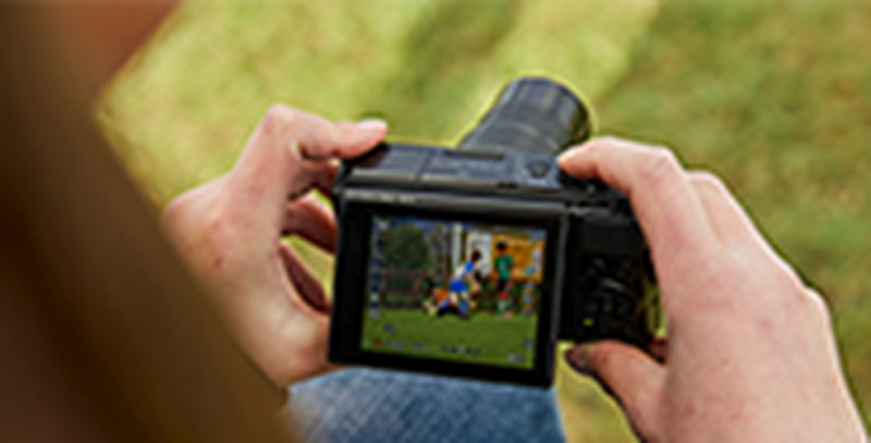 A person holding a Canon PowerShot SX740 HS looking at their shot on the flip up screen.