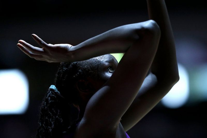 Der Kopf und die Schultern eines Netzballspielers, der die Arme über dem Kopf angewinkelt hält, während er aus dem Stand nach einem Ball springt.