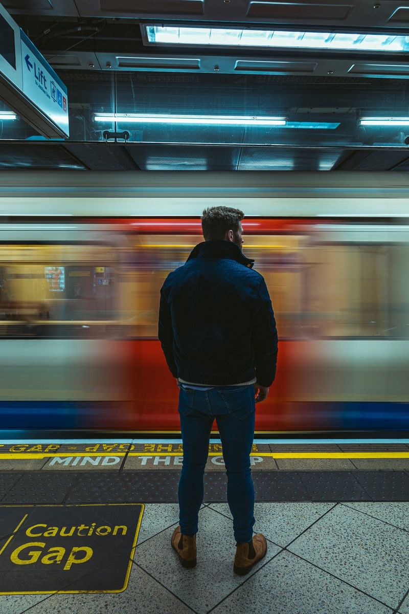 Street photography of a person watching and waiting on a platform as a train speeds past. The person is completely in focus while the train carriage is blurred.