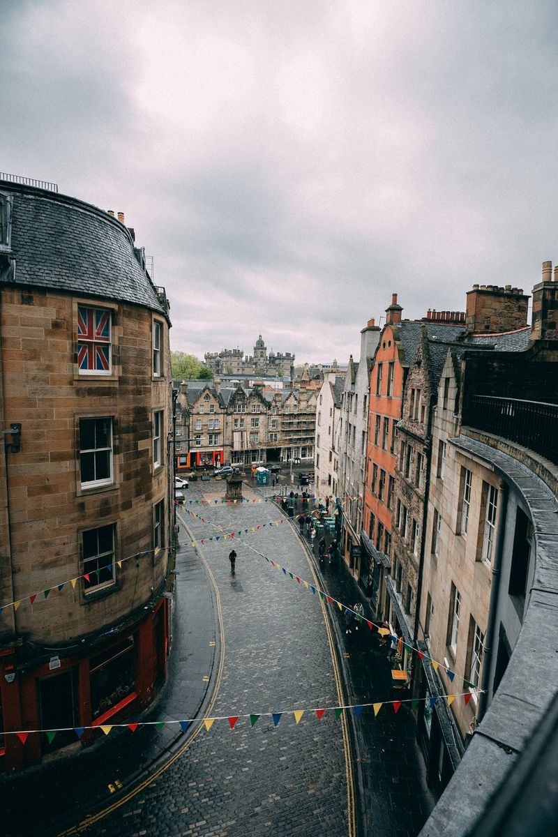A cobbled and winding Glaswegian street taken from above. Colourful bunting is strung between the buildings on either side. Taken by street photographer Andres McNeill. 