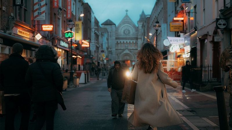 A woman running down a bustling street at dusk.