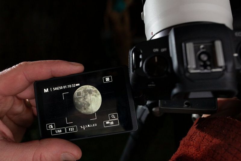 A person adjusting the vari-angle screen of their Canon EOS RP as they photograph the Moon.