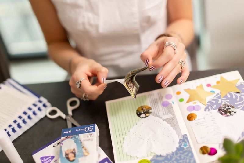 Bir kullanıcı, Canon Zoemini 2 yazıcı ile basılmış bir fotoğrafı karma günlük sayfasına yapıştırmak üzere fotoğrafın arka katmanını soyuyor.