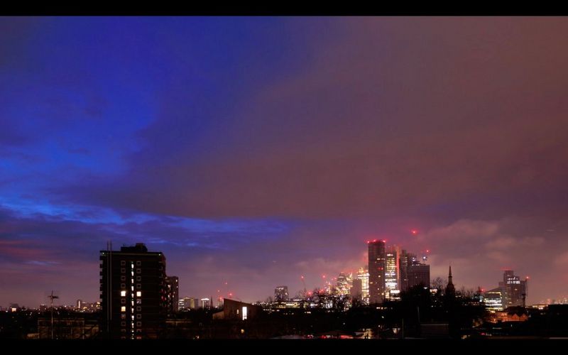 Panorama města při východu slunce se zvlněnými mraky nad hlavou.