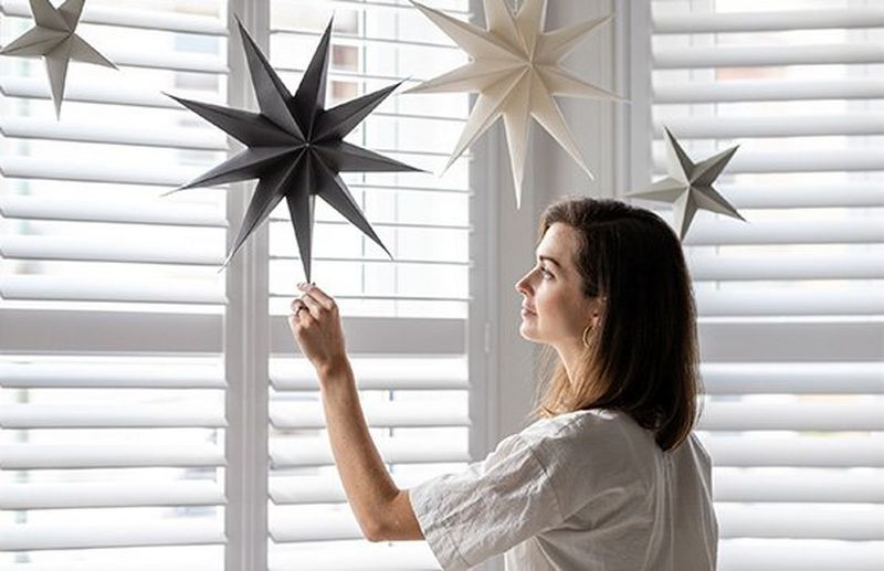A women touches a paper star hanging from her ceiling.