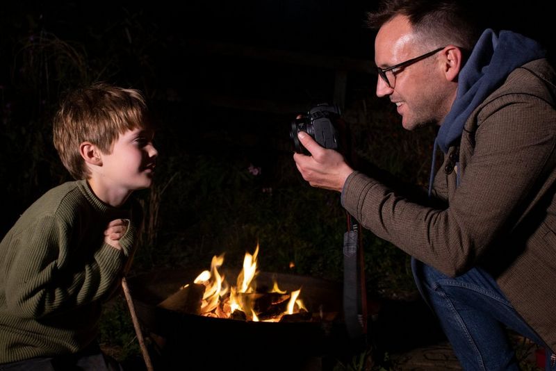 צלם מצלם דיוקן תקריב של ילד לצד מדורה.
