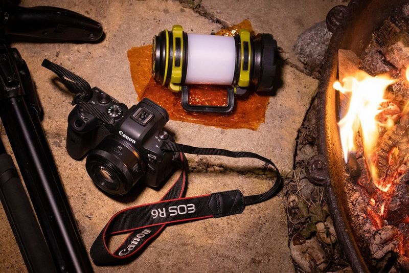 מצלמת Canon, חצובה, ג'ל כתום ומנורה ניידת בקצה בור אש.