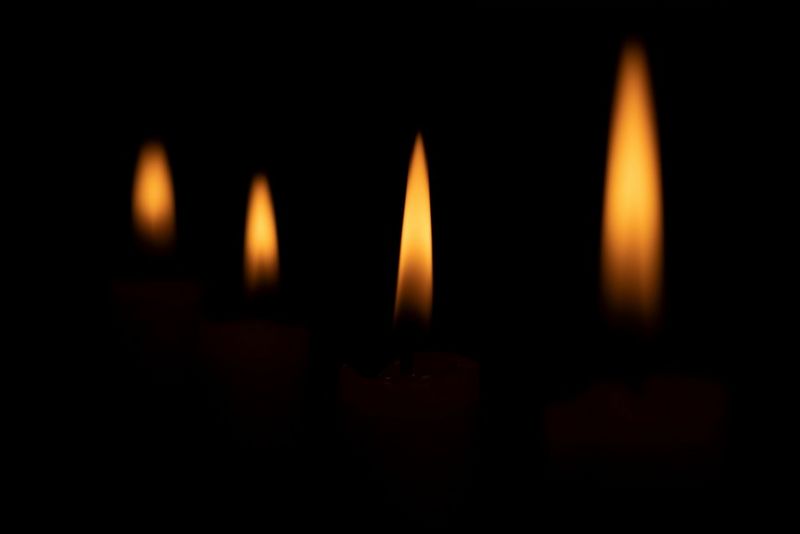 שורה של נרות שנחשפים כך שרק הלהבות נראות לעין על רקע שחור.