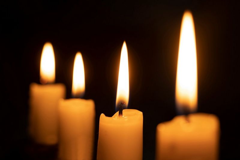 שורה של נרות שנחשפים כך שהפמוטים גלויים, בעוד שהלהבות לבנות, חסרות פרטים ומטושטשות.