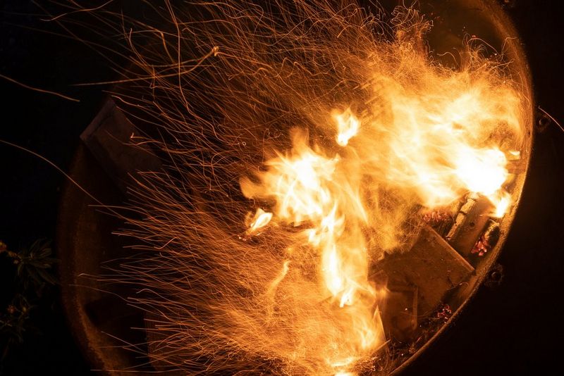 חשיפה ארוכה של מדורה, עם גחלים מרחפות שיוצרות שובלי אור ארוכים.