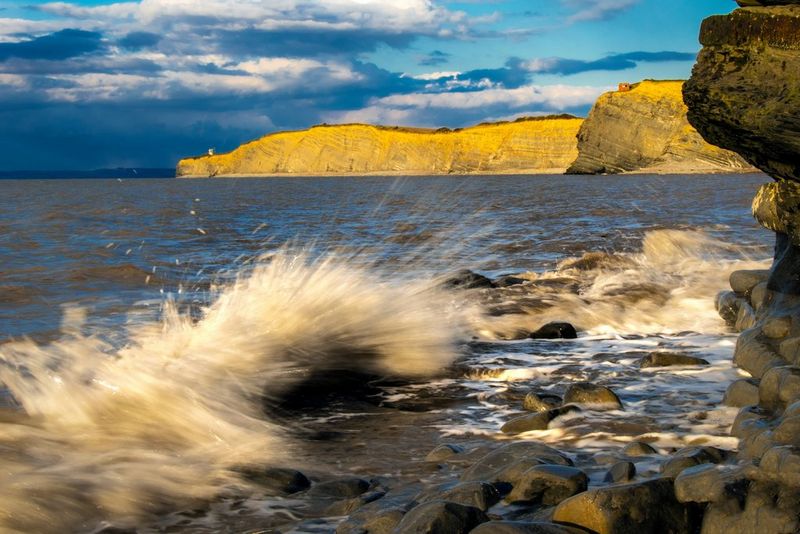 De petites vagues s'écrasent contre des pierres sur la rive d'une plage.