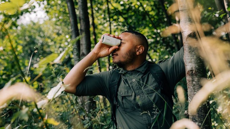 A man standing among the trees using the PowerShot ZOOM.